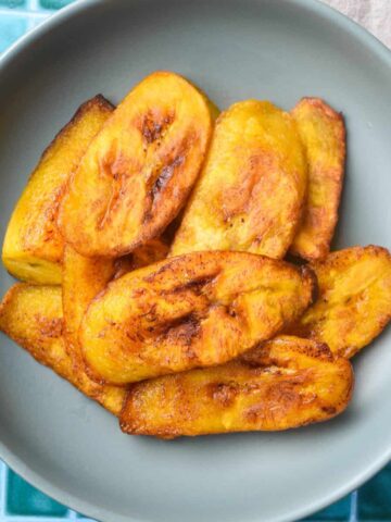 Overhead shot of fried sweet plantains in a blue bowl.