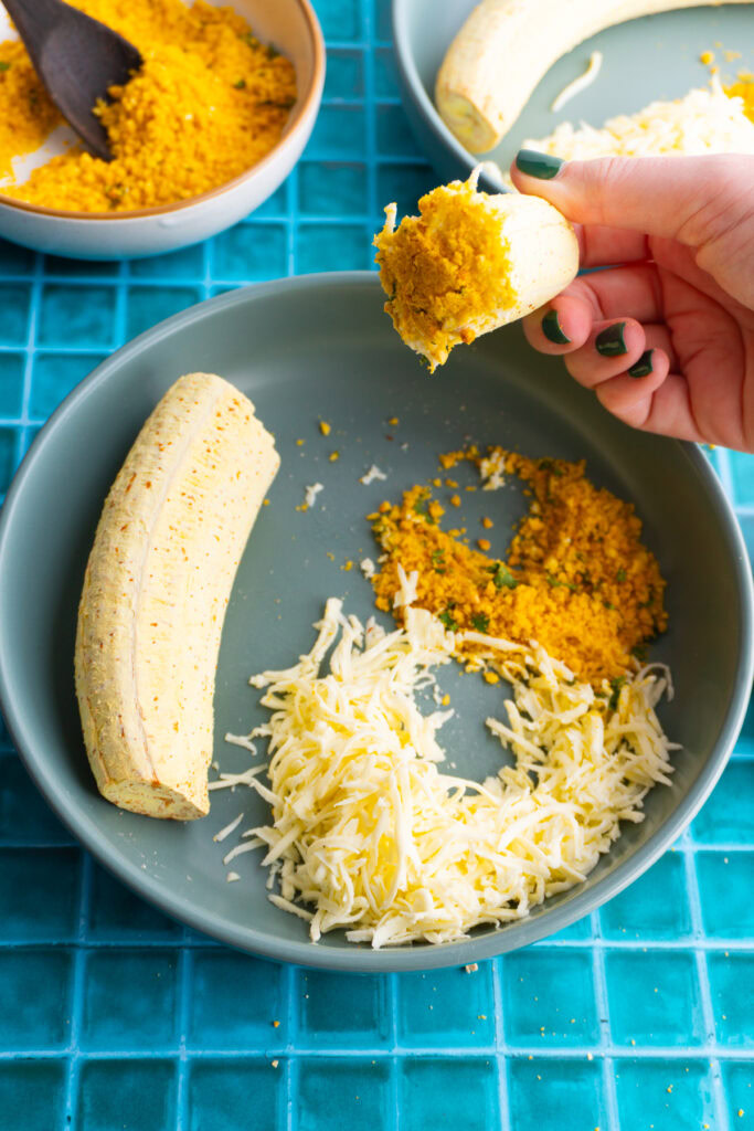 Dipping the roasted plantain in cheese and then salprieta.