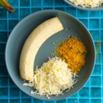Roasted green plantain with shredded cheese and salprieta in a shallow bowl.